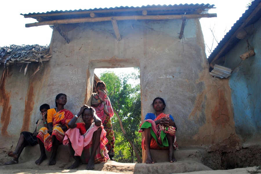 Santhal tribal women sit in a doorway of a home in a village where a woman was gang raped