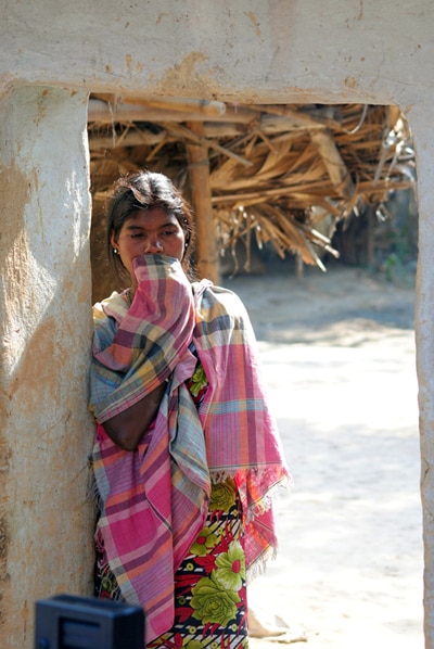 A Santhal tribal women stands in the doorway of a home in a village where a woman was gang raped