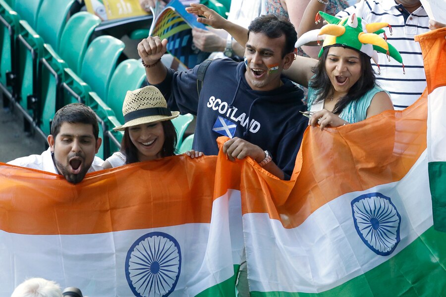 Indian fans wave their national flag and cheer as they wait for the opening ceremony for the Commonwealth Games 2014 in Glasgow, Scotland