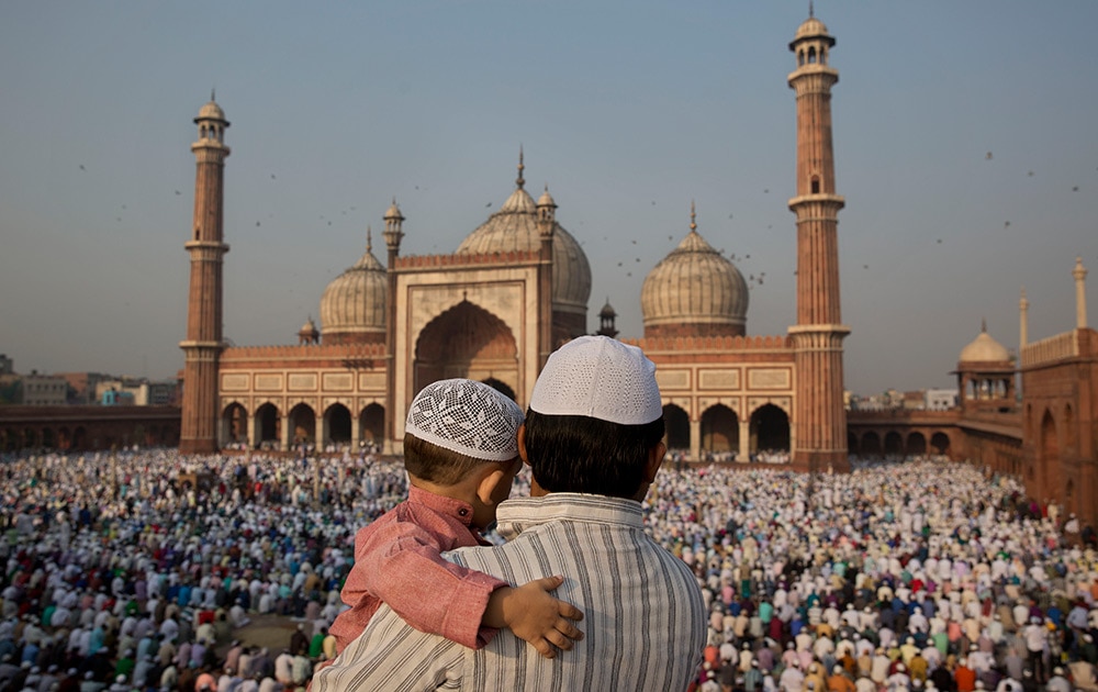 A man carries a child as they gather to offer prayers at Jama Masjid mosque in New Delhi. Muslims around the world celebrate Eid al-Adha, or the Feast of the Sacrifice, to commemorate the prophet Abraham's offering for his son to god. 