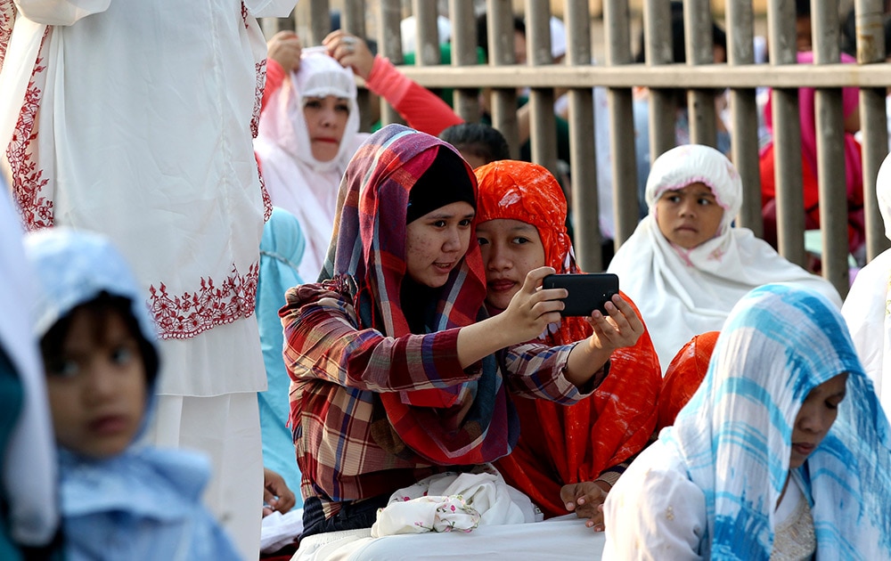 Muslim women take a selfie before a morning prayer marking the Eid al-Adha holiday on a street in Jakarta, Indonesia.