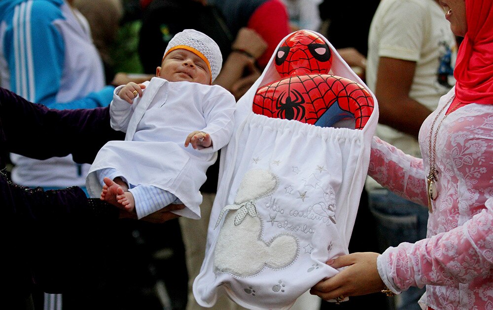A woman hold up her baby as another holds up a Spiderman balloon as Egyptians celebrate following the early morning prayers marking Eid al-Adha, a three-day Muslim holiday that started Saturday across much of the Middle East, in Cairo, Egypt.