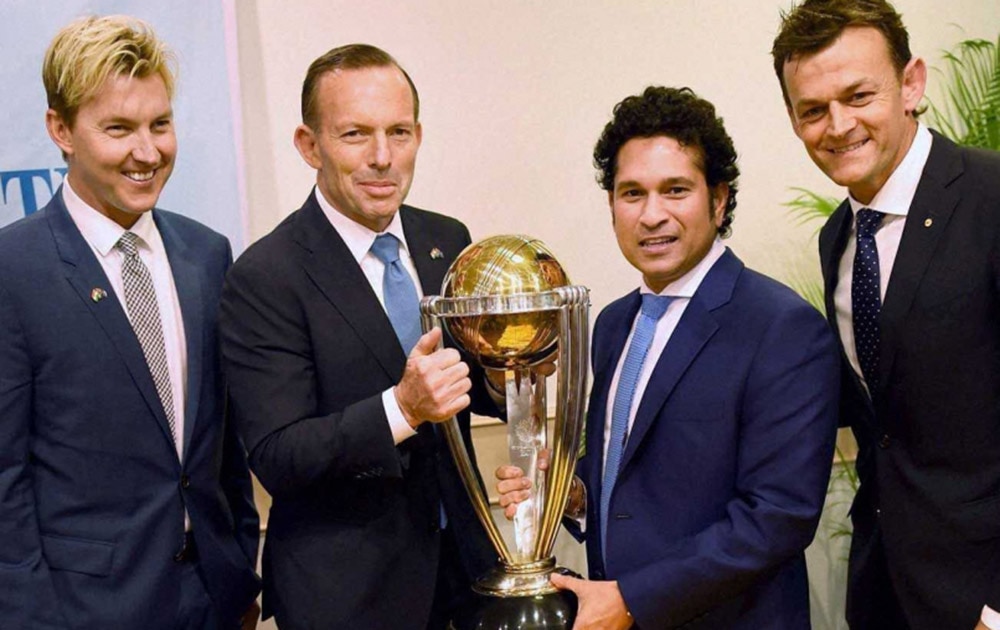 Australian Prime Minister Tony Abbott and legendary cricketer Sachin Tendulkar flanked by former Australian cricketers Adam Gilchrist and Brett Lee pose with the Cricket World Cup trophy during a sporting event.
