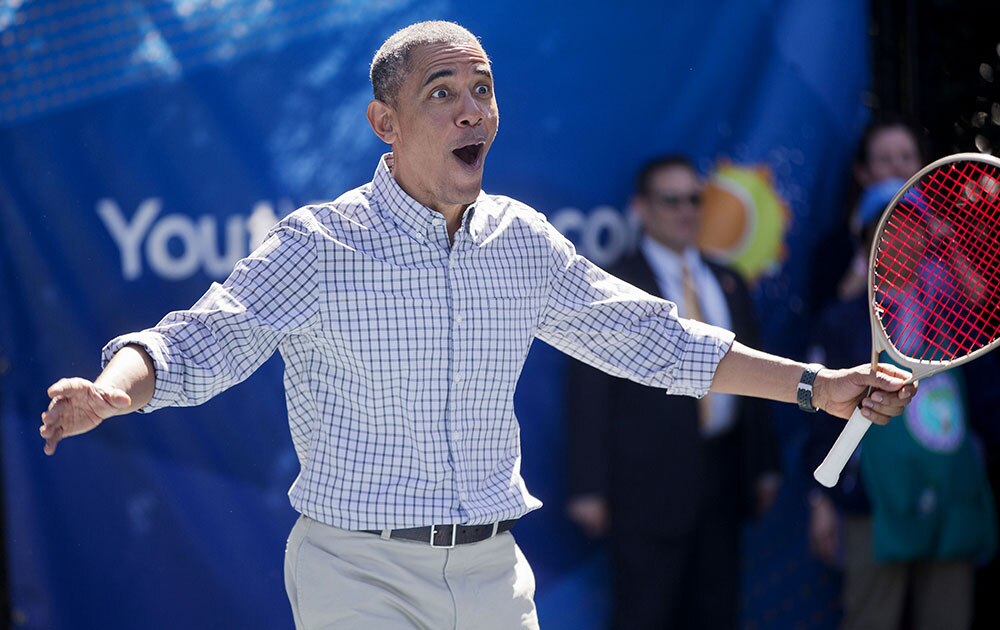 President Barack Obama reacts to scoring on Caroline Wozniacki a Danish professional tennis player as he plays tennis during the White House Easter Egg Roll on the tennis court on the South Lawn of the White House in Washington.
