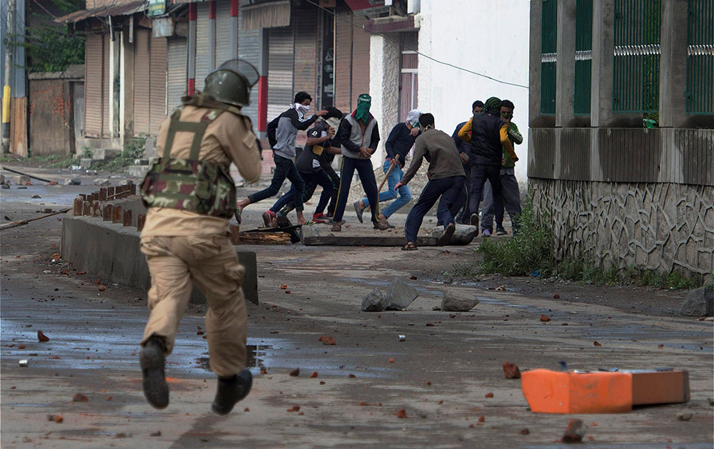 A security jawan chasing away protesters during a clash in Srinagar