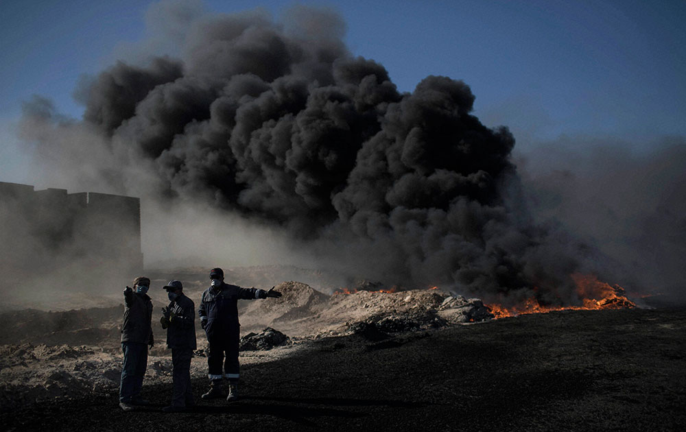 Oil workers try to extinguish burning oil fields in Qayara, south of Mosul