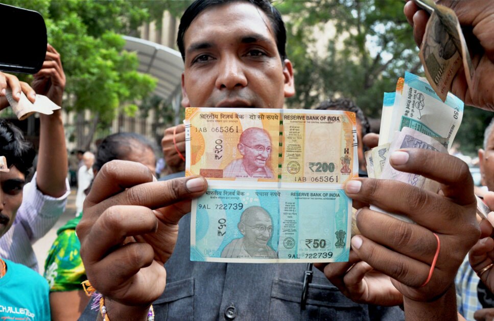 A man shows new currency notes of Rs 200 and Rs 50