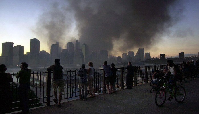 Pedestrians watch as smoke billows from the remains of the World Trade Center