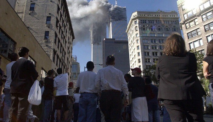 Pedestrians in lower Manhattan watch smoke billow from New York's World Trade Center